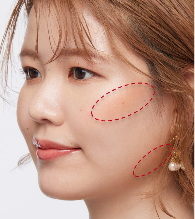 ベース型の顔にオレンジ系チークをほお骨の高い位置に斜め楕円形に入れ、フェイスラインにもチークをのせた例