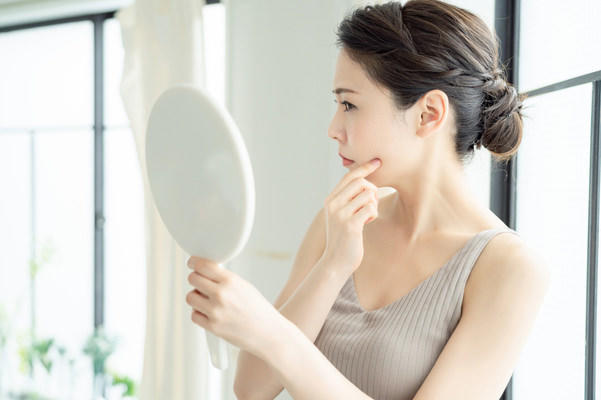 鏡を見ている不安そうな表情の女性