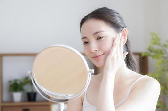 30代くらいの女性が鏡を見ている画像