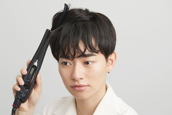 ヘアアイロンで動きをだす男性の画像