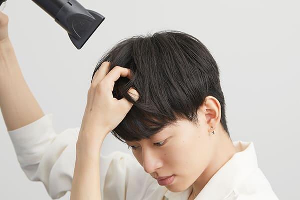 ドライヤーを上からあてる男性