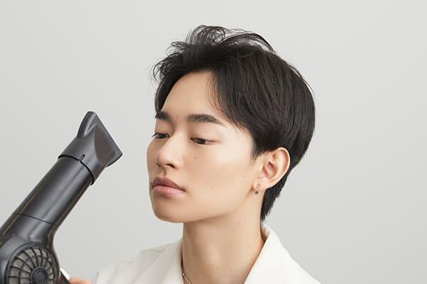 ドライヤーで前髪を乾かす男性