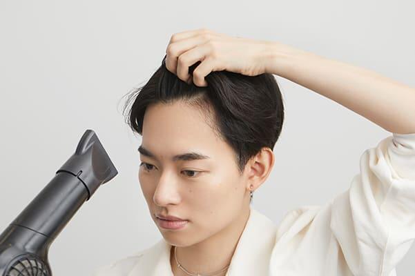 下からドライヤーをあてて前髪を乾かす男性