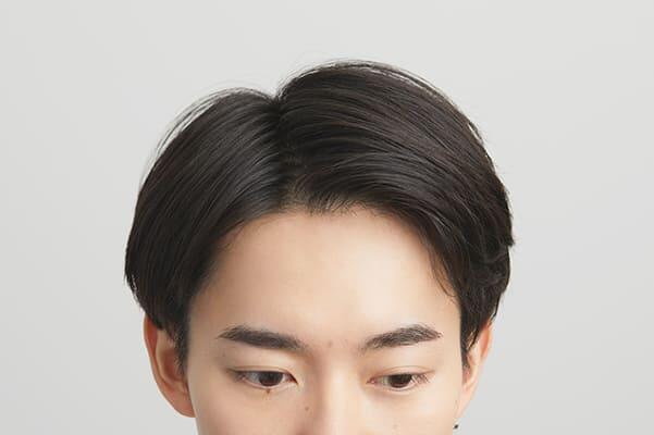 センターより少しサイドの位置で分け目を作る男性