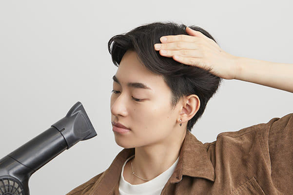 前髪にドライヤーをあててセットする男性