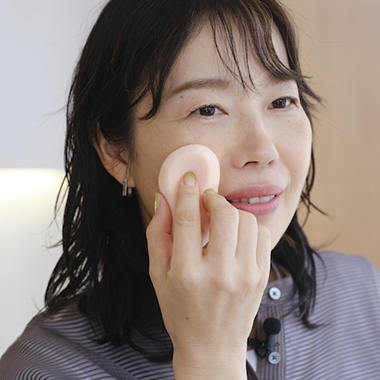 スポンジを顔にあてている女性