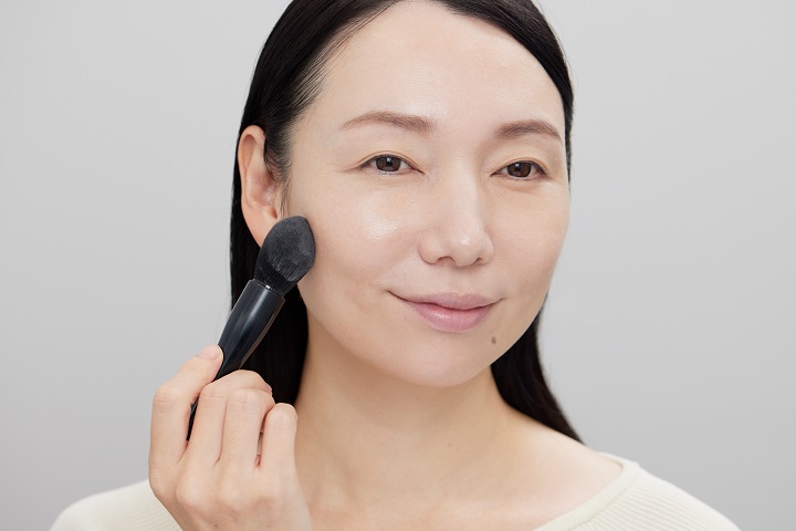 フェイスパウダーをブラシで塗っている女性