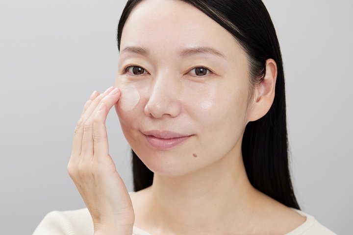 下地をほおに塗っている女性