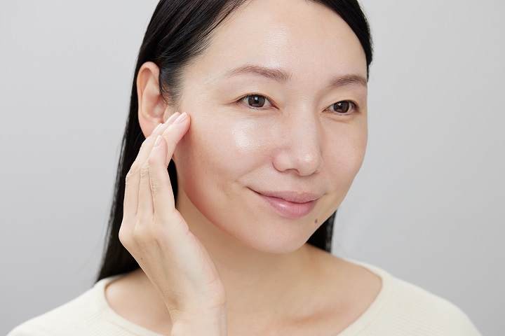 下地をほおに塗っている女性