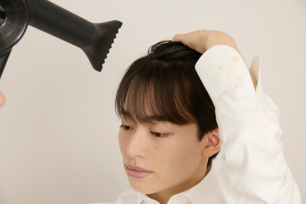 ドライヤーで前髪を流す男性