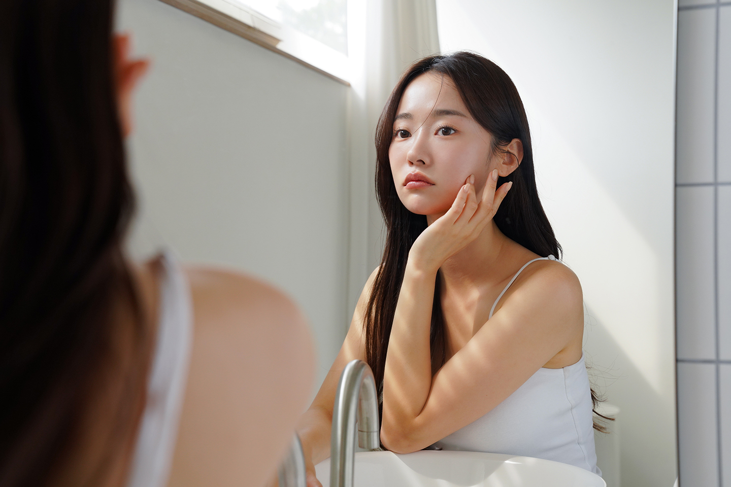 鏡をみて肌の状態を確認している女性