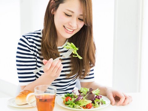 肌の健康を意識してビタミン豊富な野菜を嬉しそうに食べる女性